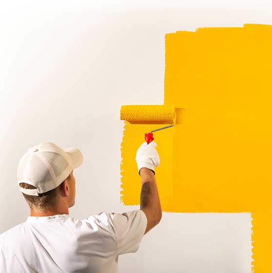 Maler streicht Wand mit gelber Farbe